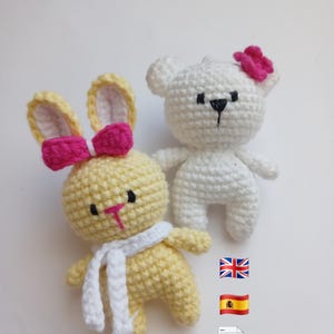 May include: Two crocheted stuffed animals: a yellow bunny with a pink bow and white scarf, and a white bear with a pink bow. Both have black eyes and are handmade. The bunny has yellow ears and a pink nose. The bear has a black nose.