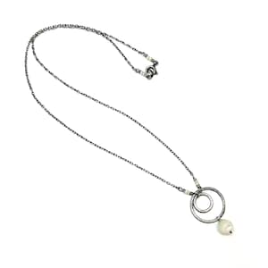 May include: A silver-toned necklace featuring a delicate chain and a pendant with two interlocking circles. A single, white pearl dangles from the bottom circle. The necklace is displayed against a white background.