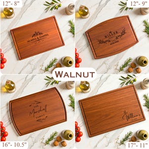 May include: Four walnut cutting boards with engraved names and dates. The boards vary in size, with the largest measuring 17 inches by 11 inches and the smallest 12 inches by 8 inches. Each board has a juice groove and is surrounded by olive oil, tomatoes, and herbs.