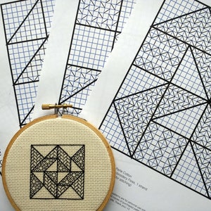 Peut inclure: Gros plan d'un projet de point de croix terminé dans un cerceau à broder en bois. Le motif est un motif géométrique noir et blanc. Le motif est également présenté sur trois feuilles de papier quadrillé.