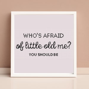 May include: White framed print with the text "WHO'S AFRAID of little old me? YOU SHOULD BE" in black cursive font on a light purple background.