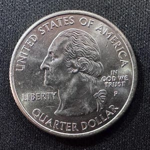 May include: A United States quarter dollar coin. The obverse features a profile of George Washington, with the inscriptions "LIBERTY", "IN GOD WE TRUST", and "QUARTER DOLLAR". The coin is silver in color.