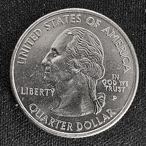 May include: A silver United States quarter coin. The obverse features a profile of George Washington, with the inscriptions "LIBERTY", "UNITED STATES OF AMERICA", and "QUARTER DOLLAR". The coin also includes the phrase "IN GOD WE TRUST".
