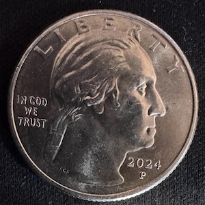 Op de afbeelding: Een zilveren 2024 kwartmunt met een profiel van George Washington, met de inscripties "LIBERTY" en "IN GOD WE TRUST". De munt heeft een "P" muntteken.