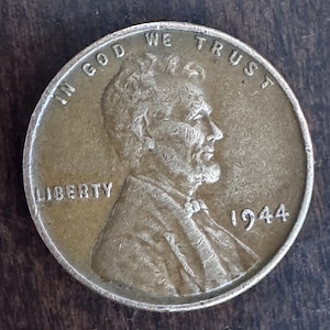 May include: A copper-colored 1944 Lincoln penny. The coin features a profile of Abraham Lincoln, the word "LIBERTY", and the phrase "IN GOD WE TRUST". The year "1944" is visible.