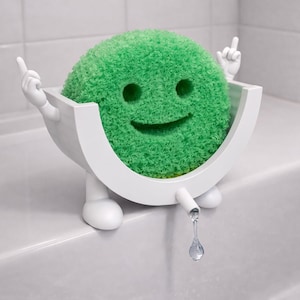 May include: A whimsical green sponge with a smiling face, seated in a white bathtub-shaped holder. The holder has arms and legs, with one hand giving the middle finger. A water droplet hangs from a spout.