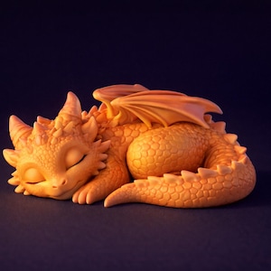 Könnte beinhalten: Eine schlafende, orangefarbene Drachenfigur mit geschlossenen Augen, Hörnern und strukturierten Schuppen. Der Drache hat gefaltete Flügel und ist auf einer dunklen Oberfläche zusammengerollt. Die Figur ist ein Fantasy-Sammlerstück.