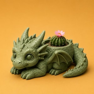 May include: A green dragon-shaped planter with a cactus and pink flower. The dragon has large eyes, horns, and wings. The planter is on an orange background.