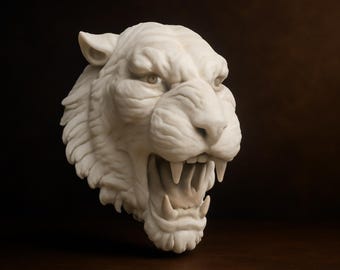 Peut inclure: Sculpture blanche d'une tête de tigre rugissant, avec une gueule ouverte et des dents acérées. La sculpture texturée est mise en valeur sur un fond marron foncé, soulignant l'expression féroce.