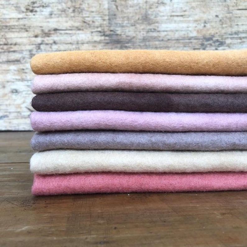 May include: A stack of eight different colored felt squares in shades of brown, pink, beige, and orange. The felt squares are arranged in a gradient from darkest to lightest.