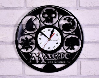 Puede incluir: Reloj de vinilo negro con el logotipo de Magic: The Gathering y cinco símbolos que representan los cinco colores de maná: blanco, azul, negro, rojo y verde.