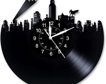 Könnte beinhalten: Eine schwarze Schallplattenuhr mit einer Silhouette einer Stadt und einem Batman-Logo. Das Zifferblatt der Uhr hat weiße Zahlen und Zeiger, und der Text "Live" ist auf dem Zifferblatt gedruckt.