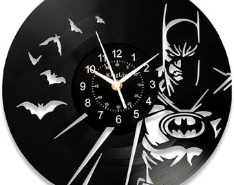 Könnte beinhalten: Eine schwarze Schallplattenuhr mit einer Silhouette von Batman mit einem Fledermaussymbol auf der Brust. Das Zifferblatt der Uhr hat einen weißen Hintergrund mit schwarzen Zahlen und Zeigern. Die Uhr ist von einem schwarzen Hintergrund mit einer Silhouette von Fledermäusen umgeben.