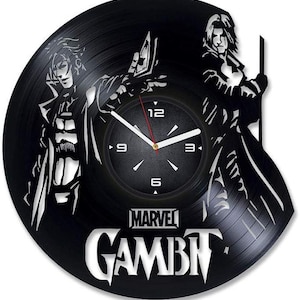 May include: Black vinyl record clock featuring a silhouette of two characters from the Marvel Comics series Gambit. The clock face is white with black numbers and hands. The text "MARVEL GAMBIT" is printed below the clock face.