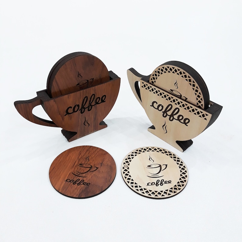 May include: Set of six wooden coasters with a coffee cup design. The coasters are in the shape of a coffee cup and have a brown and natural wood finish. The coasters are stacked in two sets of three, with the top coaster in each set showing the coffee cup design.