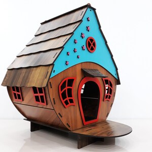 May include: A wooden birdhouse with a blue roof and red accents. The roof has pink stars and a small round window. The birdhouse has a small door and two windows.