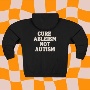 May include: Black zippered hoodie with the text "Cure ableism not autism" in white.