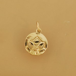 May include: A gold-colored pendant charm featuring a detailed lotus flower design. The charm is round and has a smooth, polished finish.