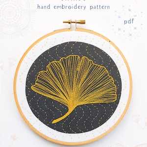 May include: A gold embroidered ginkgo leaf on a black fabric background in a wooden embroidery hoop. The text "GINKGO" and "hand embroidery pattern" is above the hoop. The text "pdf" is in the top right corner of the image. The text "COZYBLUE handmade" is at the bottom of the image.