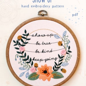 Peut inclure: Motif de broderie à la main dans un cercle en bois. Le design comprend les mots "show up, be true, be kind, keep going" avec des accents floraux et de feuilles roses, oranges et vertes. Le texte "COZYBLUE handmade" est en bas.