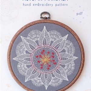 May include: A hand-stitched embroidery pattern of an autumn mandala in a wooden embroidery hoop. The mandala is stitched in white thread on a gray fabric background with red and yellow accents. The text "AUTUMN MANDALA" and "hand embroidery pattern" is above the hoop. The text "pdf" is in the upper right corner of the image. The text "COZYBLUE handmade" is below the hoop.