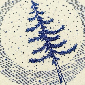 Może przedstawiać: Haftowany obręcz z niebieskim drzewem sosnowym na tle nocnego nieba.