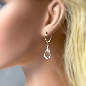 May include: Silver dangle earrings with a clear teardrop-shaped crystal.