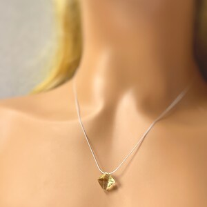 May include: A delicate silver chain necklace with a small, square-shaped, yellow gemstone pendant.