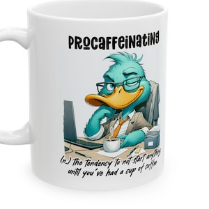 May include: White ceramic coffee mug with the word "PROCRAFFEINATING" and a cartoon duck wearing glasses, a tie, and a blazer. The mug also has the definition of the word. A laptop and coffee cup are on the desk.
