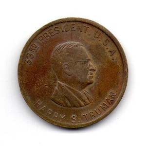 May include: A bronze-colored coin featuring a profile of Harry S. Truman, the 33rd President of the U.S.A. The coin's edge is inscribed with "33RD PRESIDENT U.S.A." and "HARRY S. TRUMAN".