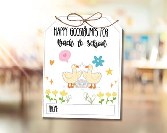 May include: A white tag with the text "HAPPY GOOSEBUMPS FOR Back to school" in black. Two cartoon geese face each other above a wavy line. The tag has a brown string and includes a space to write "FROM:"