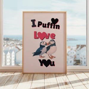 Könnte beinhalten: Ein rosa-weißer Druck mit dem Text "I Puffin Love You" in Schwarz und rosa Herzen. Zwei Cartoon-Papageientaucher sind in der Mitte des Drucks abgebildet und schauen sich an.