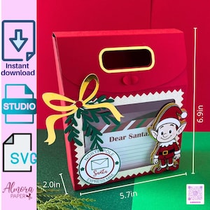 Puede incluir: Una caja de regalo roja con temática navideña con una ventana, un lazo amarillo y un recorte de elfo. La caja mide 14,5 cm de ancho y 17,5 cm de alto. El texto "Dear Santa" es visible. La caja está etiquetada como "North Pole Santa Express Mail".