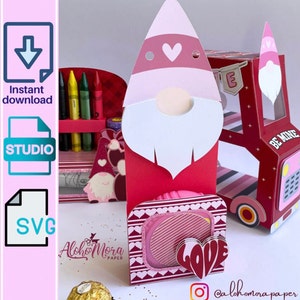 Puede incluir: Una caja de gnomo de San Valentín roja y rosa con una ventana en forma de corazón y la palabra "LOVE" en la parte delantera. La caja está decorada con rayas rosas y blancas y corazones.