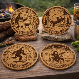 May include: Set of four round cork coasters with Bigfoot and alien illustrations. Designs include "Burger Bash," "Chill Vibes Only," "Skate & Discover," and "Cosmic Seekers." Each coaster features a brown Bigfoot graphic and text.