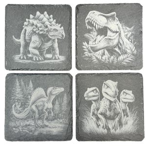 May include: A set of four square dark gray slate coasters, each featuring a detailed white laser-engraved dinosaur illustration. The designs include an ankylosaurus, a roaring tyrannosaurus rex, a spinosaurus, and a trio of velociraptors.