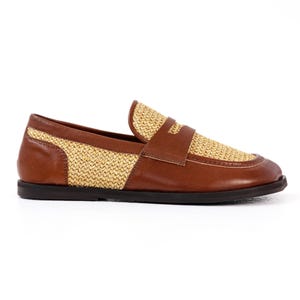 May include: A brown leather loafer with a woven straw-like design on the vamp and heel. The shoe has a dark brown sole and a strap across the top. A stylish and comfortable footwear option.