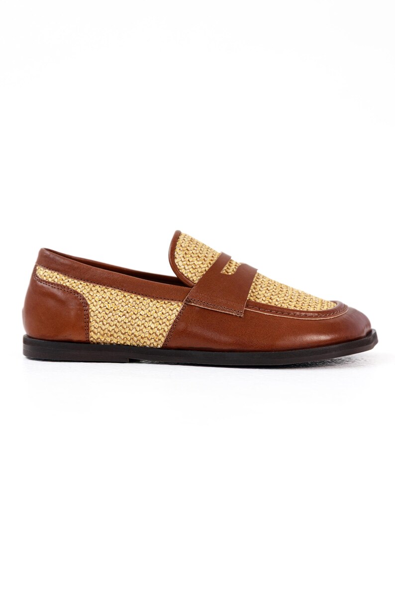 May include: A brown leather loafer with a woven straw-like design on the vamp and heel. The shoe has a dark brown sole and a strap across the top. A stylish and comfortable footwear option.