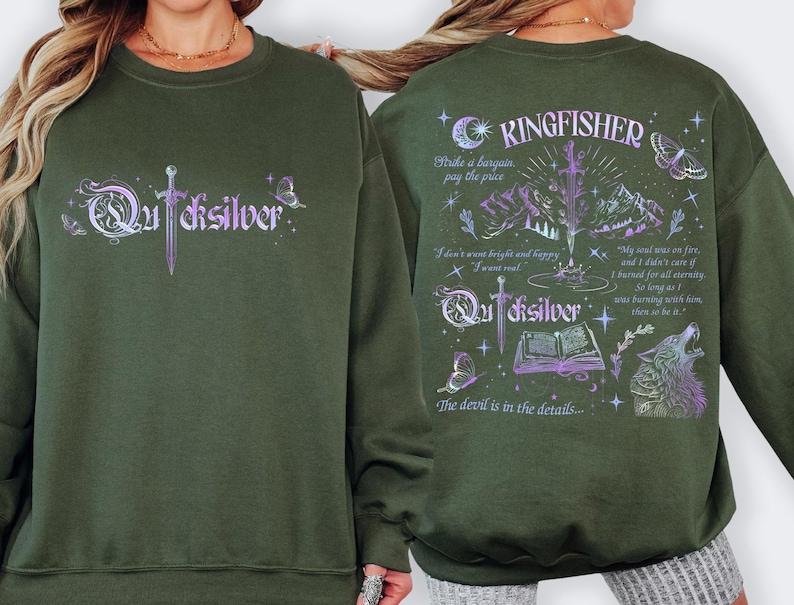 K&ouml;nnte beinhalten: Ein olivgr&uuml;nes Sweatshirt mit dem Wort "Quicksilver" in einer stilisierten Schriftart auf der Vorderseite, mit einem Schwertdesign. Auf der R&uuml;ckseite befindet sich das Wort "Kingfisher" und ein grafisches Design mit einem Wolf, Bergen und Text.