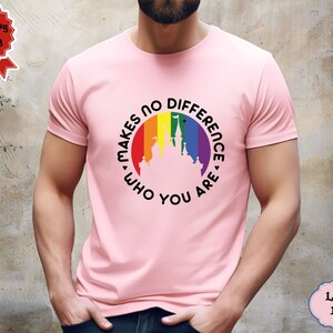 May include: A light pink t-shirt with a rainbow-colored circle featuring a silhouette of a castle and the text "It Makes No Difference Who You Are".