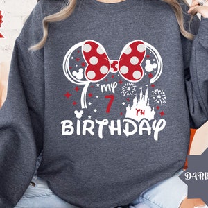 May include: Dark grey sweatshirt with a white graphic of Minnie Mouse ears, a red bow with white polka dots, a castle, fireworks, and the text "My 7th Birthday".