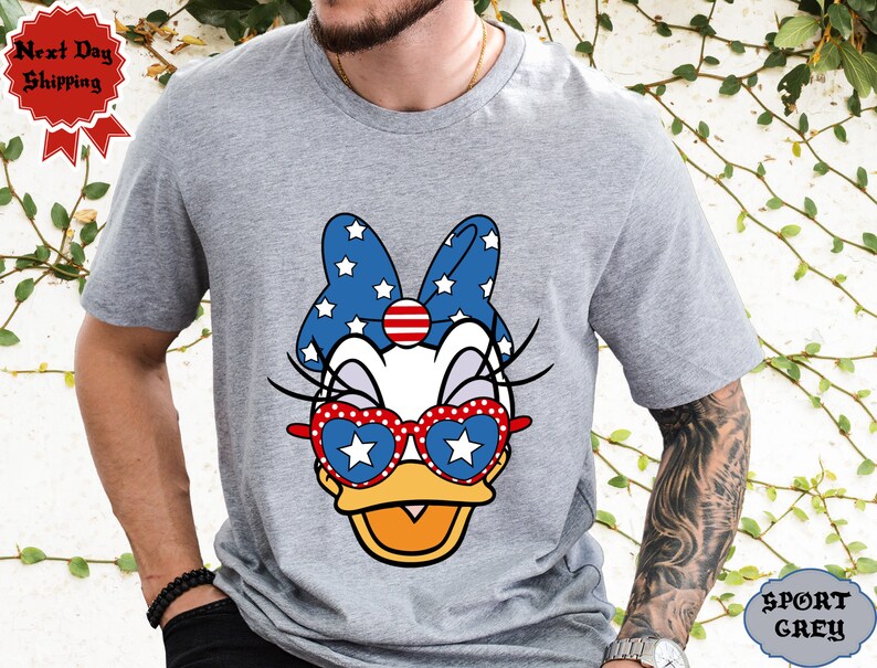May include: A grey t-shirt with a cartoon image of a duck wearing red, white, and blue sunglasses and a bow with stars. The text "SPORT GREY" is visible in the bottom right corner of the image.