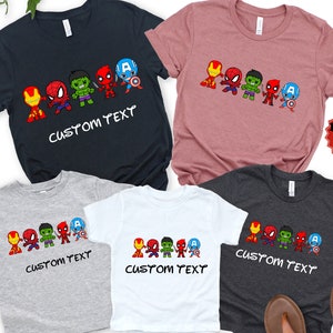 May include: Set of five t-shirts featuring a line of cartoon superheroes, including Iron Man, Spiderman, Hulk, Deadpool, and Captain America. The shirts are in various colors, including black, gray, white, and pink. The shirts have the text "CUSTOM TEXT" printed on them.