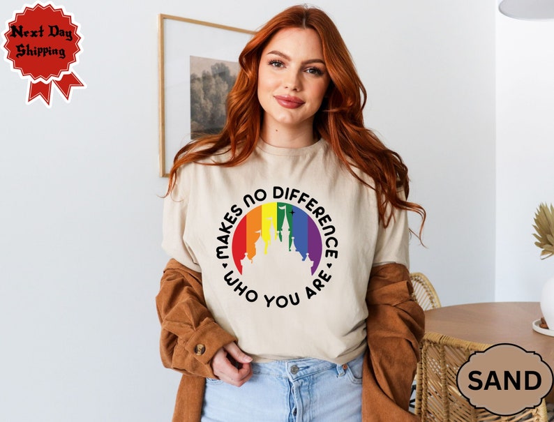 May include: A beige t-shirt with a rainbow-colored circle featuring a castle silhouette and the text "Makes No Difference Who You Are."