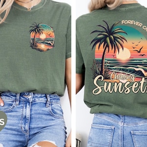 Pu&ograve; includere: T-shirt verde muschio con grafica del tramonto sul davanti e sul retro. Il davanti presenta un piccolo disegno circolare con una palma, un tramonto e l'oceano. La grafica sul retro dice "Forever Chasing Sunsets" con un design di palma, tramonto e oceano.