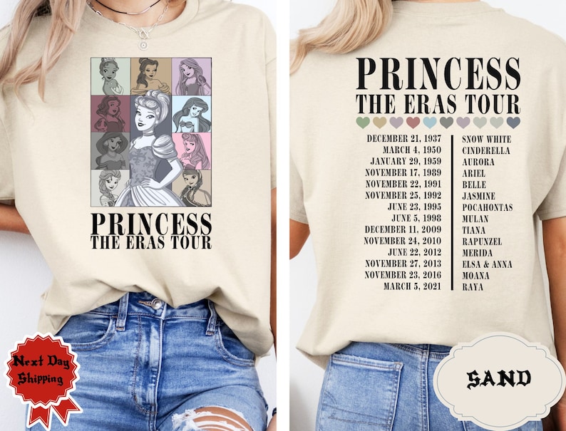 May include: A beige t-shirt with a graphic of Disney princesses and the text "Princess The Eras Tour". The back of the shirt has a list of Disney princesses and their debut dates.
