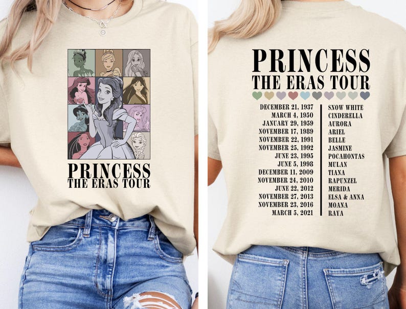 May include: A beige t-shirt with a graphic of Disney princesses and the text "Princess The Eras Tour". The graphic includes Snow White, Cinderella, Aurora, Ariel, Belle, Jasmine, Pocahontas, Mulan, Tiana, Rapunzel, Merida, Elsa and Anna, Moana, and Raya. The dates of their respective films are listed on the right side of the shirt.