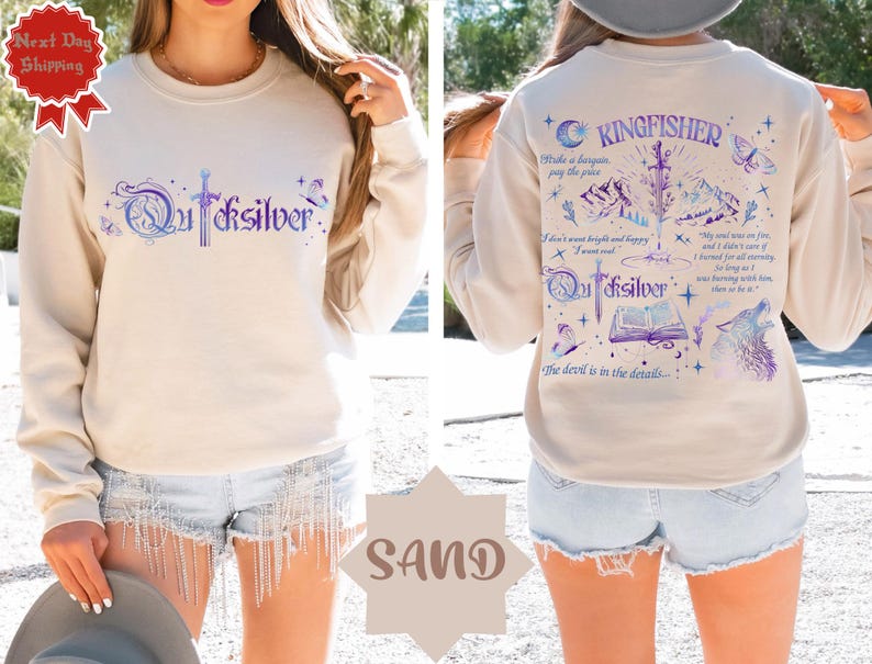 K&ouml;nnte beinhalten: Sandfarbenes Sweatshirt mit dem Wort "Quicksilver" in einer stilisierten Schrift auf der Vorderseite. Auf der R&uuml;ckseite befindet sich das Wort "Kingfisher" und ein Design mit Schwert, Bergen, Wolf und Text. Das Sweatshirt hat lange &Auml;rmel.