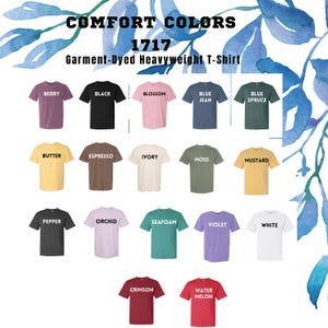 May include: A display of various colored t-shirts, including berry, black, blossom, blue jean, and blue spruce. The shirts are labeled with their color names and the text "COMFORT COLORS 1717 Garment-Dyed Heavyweight T-Shirt".