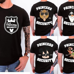 Może przedstawiać: Czarne koszulki z białymi grafikami. Jedna koszulka ma wzór tarczy z napisem "Princess Security" i głową Myszki Miki. Inne koszulki przedstawiają "Princess Security" z postaciami z kreskówek.